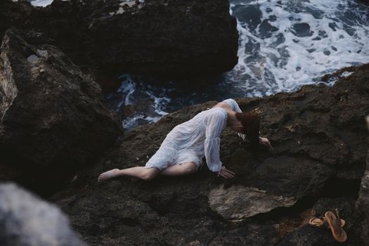 beautiful young woman lying on her back on a rocky seashore view from above. High quality photo
