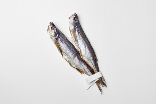 Two salted air-dried sabrefish with paper labels on tails isolated on white background with copyspace. Popular fish appetizer concept