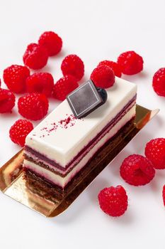 Delicate chocolate sponge cake with light mascarpone cream, sweet jellied raspberry jam, sugar icing on top and fresh ripe berries on white background