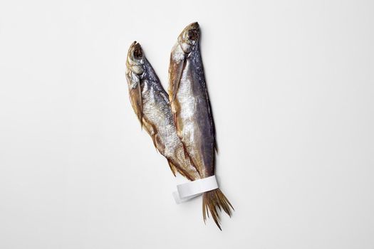 Bunch of two jerked or dried salted sabrefish with paper labels on tails isolated on white background. Traditional way of preserving fish