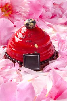 Delicate dessert on chocolate sponge cake base with airy cherry mousse covered with berry confit and with edible gold surrounded by pink peony petals. Sweet delights