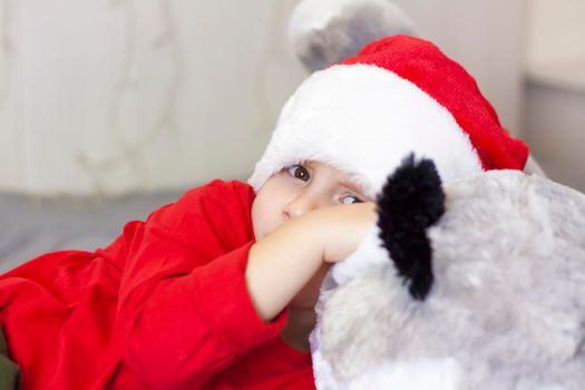 Portrait of a cute boy in a Santa Claus hat. Funny smiling child. Gifts, toys, joy, celebration. Christmas concert.