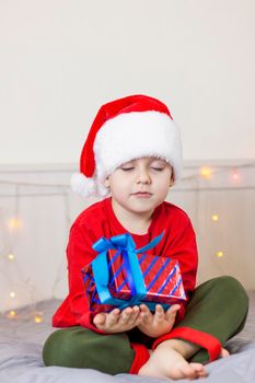 Portrait of a cute boy in a Santa Claus hat. Funny smiling child. Gifts, toys, joy, celebration. Christmas concert.