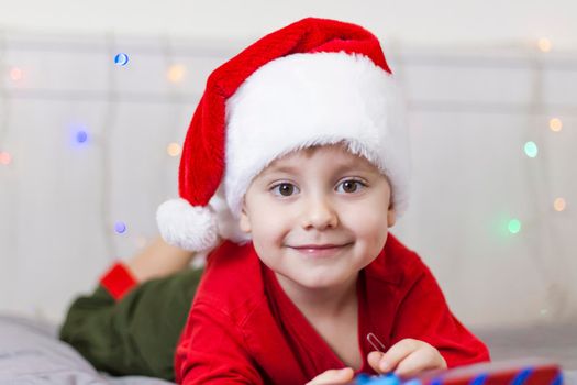 Portrait of a cute boy in a Santa Claus hat. Funny smiling child. Christmas concert.