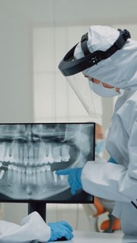 Professional stomatologist looking at teeth animation on screen and comparing model for patient dentition at clinic. Dental assistant using virtual computer technology for operation