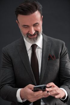 Portrait of adult businessman wearing trendy suit and sitting in modern studio on stylish chair against the black background. Horizontal mockup. High quality photo