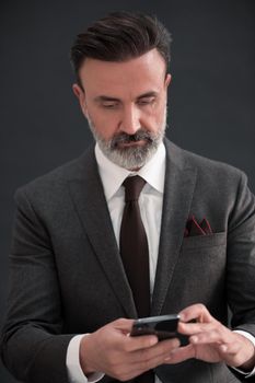 Portrait of adult businessman wearing trendy suit and sitting in modern studio on stylish chair against the black background. Horizontal mockup. High quality photo