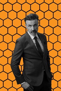 Black and white portrait of a stylish elegant senior businessman with a beard and casual business clothes against retro colorful pattern design background gesturing with hands. High quality photo