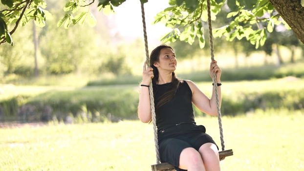 Young beautiful long-haired girl on a rope swing