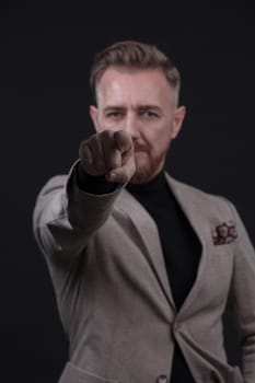 Portrait of a stylish elegant senior businessman with a beard and casual business clothes in photo studio isolated on dark background gesturing with hands. High quality photo