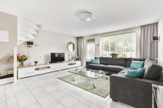 Impeccable living area with large black sofa and glass coffee table