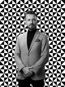 Black and white portrait of a stylish elegant senior businessman with a beard and casual business clothes against retro colorful pattern design background gesturing with hands. High quality photo