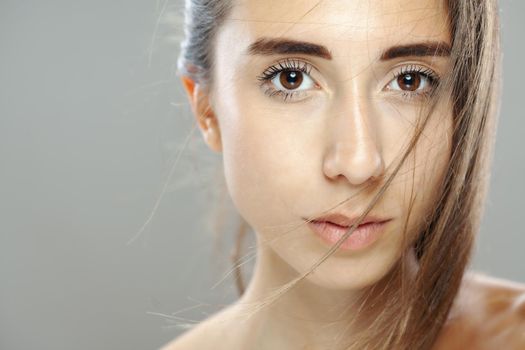 Beautiful brunette girl studio portrait. Serious face expression.