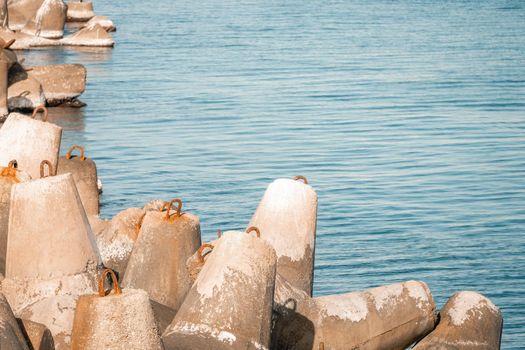 The seashore is reinforced with concrete tetrapods. Protection of the shore from blurring. Sea waves. Concrete tetrapod breakwaters lie all along the coast.