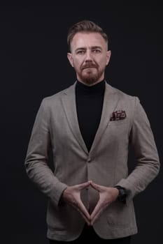 Portrait of a stylish elegant senior businessman with a beard and casual business clothes in photo studio isolated on dark background gesturing with hands. High quality photo