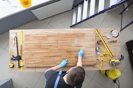 Top view of carpenter handy man lacquer wooden plank at workroom. Worker cover wood part of furniture with shiny varnish. Construction, renovation concept