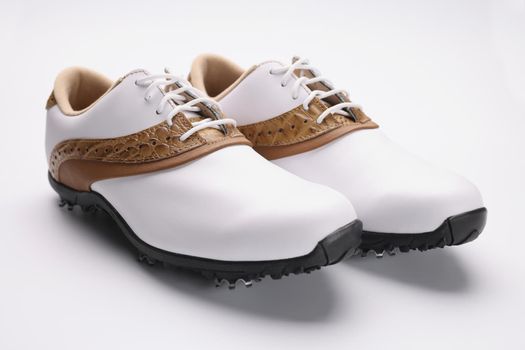 Close-up of pair of stylish fashionable shoes with unique design, white leather combines with gold, metal things on sole. Footwear, fashion, design concept