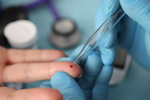 Close-up of doctor take blood of client finger with glass tube, usual procedure at clinic. Planned test for client on appointment. Medicine, clinic concept