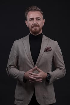 Portrait of a stylish elegant senior businessman with a beard and casual business clothes in photo studio isolated on dark background gesturing with hands. High quality photo