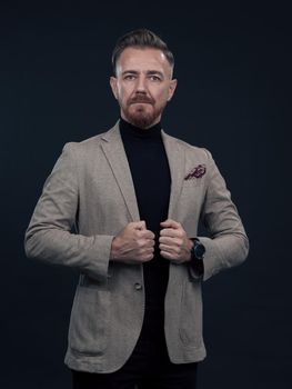 Portrait of a successful stylish elegant senior businessman with a grey beard and casual business clothes confident in photo studio isolated on dark background gesturing with hands. High-quality photo