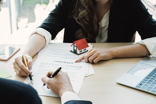 Close up of Businesswoman and customer pointing and signing agreement for buying house. Bank manager concept.