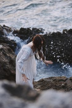 Woman in white dress rocks sea nature. High quality photo