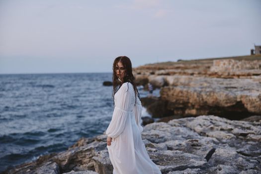 woman with wet hair in a dress on the stony shore of the ocean. High quality photo