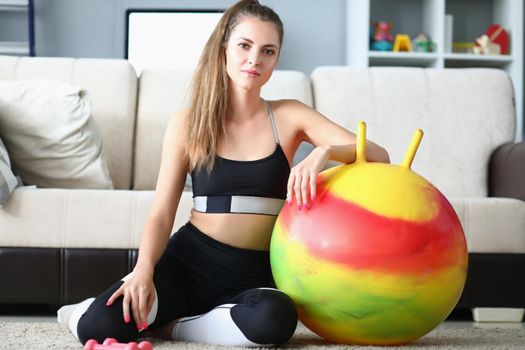 Portrait of attractive young woman pose with dumbbells and ball on floor. Girl prepare for active workout at home. Sport, physical activity, hobby concept