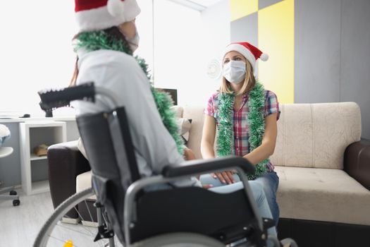 Portrait of visit friend in hospital room, relative in wheelchair, face mask for protection. Healthcare, medicine, disabled people, nursing house concept