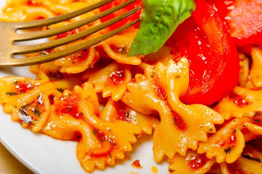 Italian pasta farfalle butterfly bow-tie with tomato basil sauce over white rustic wood table