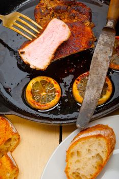 pork chop seared on iron skillet with lemon and spices seasoning