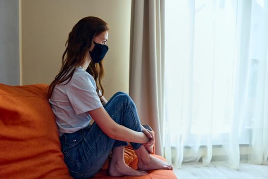 woman in black protective masks sitting on the couch at home Lifestyle. High quality photo