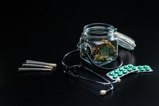 the Dry medical cannabis in a jar with a stethoscope on a black background