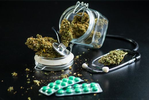 the Dry medical cannabis in a jar with a stethoscope on a black background