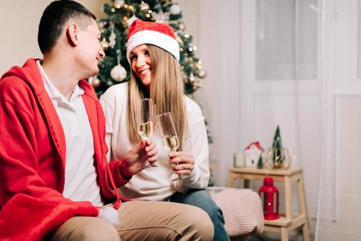 Family couple with funny face, man and woman with champagne celebrate New year after Christmas holidays. Home decor with Christmas tree.