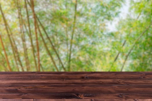 Blur green tree bamboo grove forest with wooden space forground for products montage advertising  background.