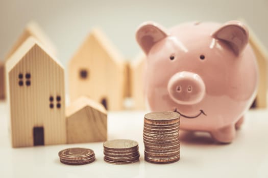 Happy saving money for home concept. Piggy bank with money and home model vintage color tone.