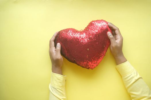 man holding big red heart on yellow background .
