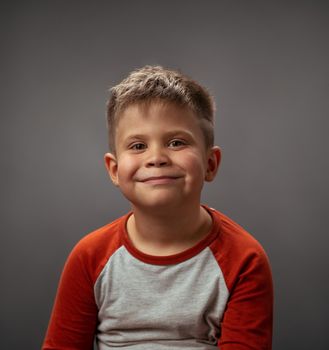 Little boy toddler adorable cute portrait. Smiling little boy full of happy feelings. Portrait, isolated over grey background. Facial expressions, emotions, feelings.