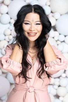 Attractive Asian Young Woman With Hands Behind her Head. Close-up portrait of an Asian Lady with a Wide Smile. Balls Background. High quality photo