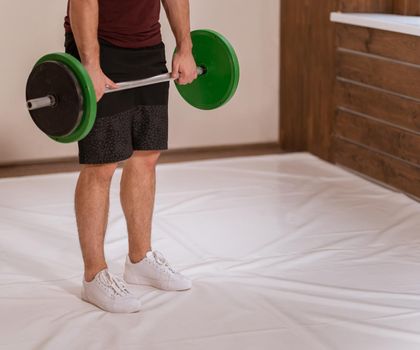 Sports equipment for training. Weightlifting young man standing gripped a black and green weight set, equipment for weight training concept. Weight loss, healthy lifestyle concept.