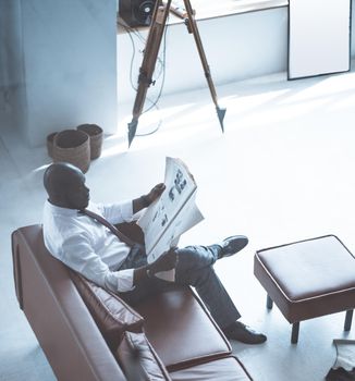 CEO Sits on the Couch with a Newspaper in his Hands and Reads the Latest News. Close-up. Top View. Big Boos. High quality photo