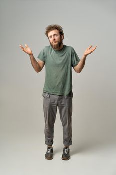 I don't know gesturing with both hands. Handsome man with curly hair isolated on white background. Portrait of confused young man on white background.