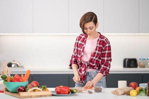 Cooking at home for loving family. Pretty young woman cutting ingredients on table cooking a lunch or dinner standing in the kitchen. Healthy food living. Healthy lifestyle.