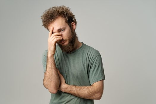 Ashamed or facepalm hiding face young man covered his with hand pry with his eye, curly hair in olive t-shirt isolated on white background. Portrait of ashamed young man.