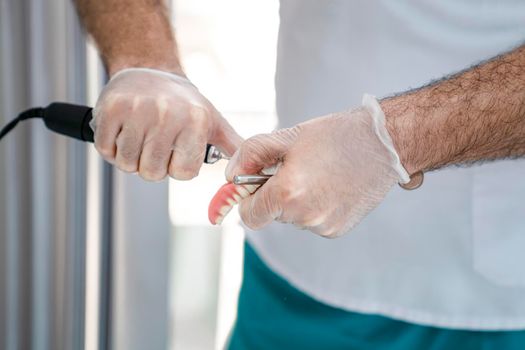 The dentist corrects the denture. Close-up