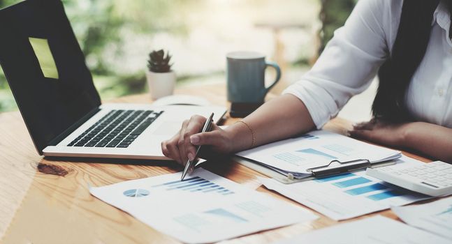 Business woman using calculator for do math finance on wooden desk in office and business working background, tax, accounting, statistics and analytic research concept.