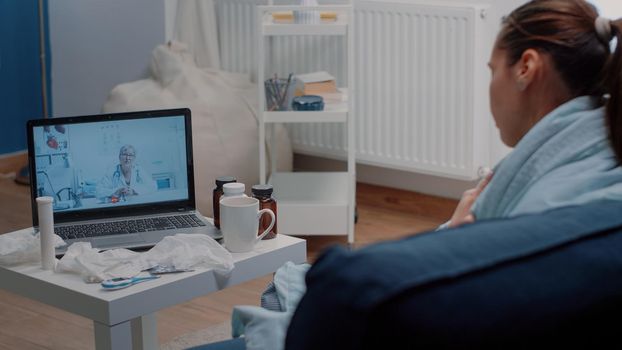 Sick woman talking to doctor on video call conference for telemedicine, asking for medical advice and disease treatment. Patient using laptop for online remote consultation with medic