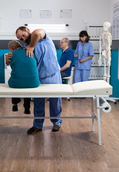 Osteopathy specialist relieving pressure from back bones of aged patient for physiotherapy. Chiropractor giving support and helping senior woman with spinal cord ache for physical recovery