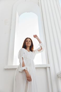 Woman in white dress rays sun window posing. High quality photo